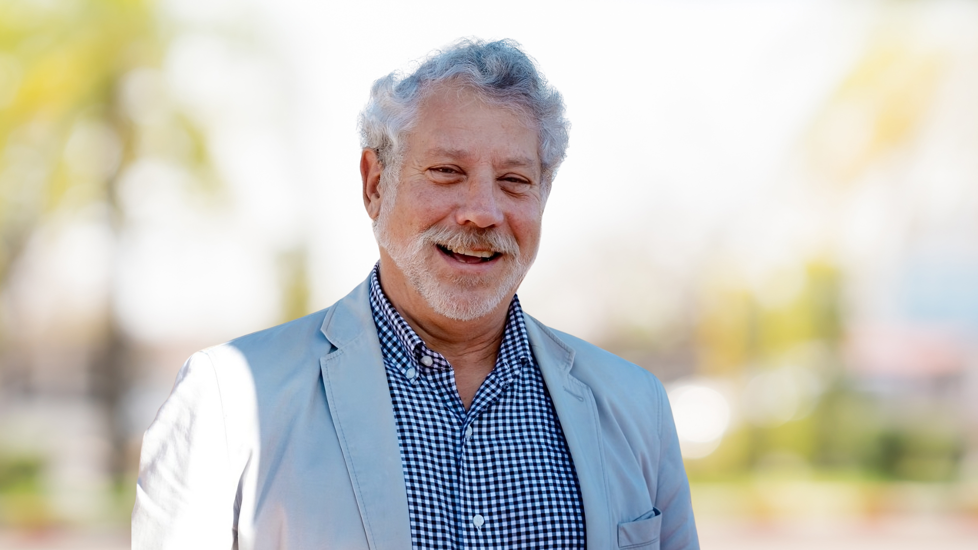 Portrait of Benson Honig, a smiling White man with a beard, in a light blue suit.