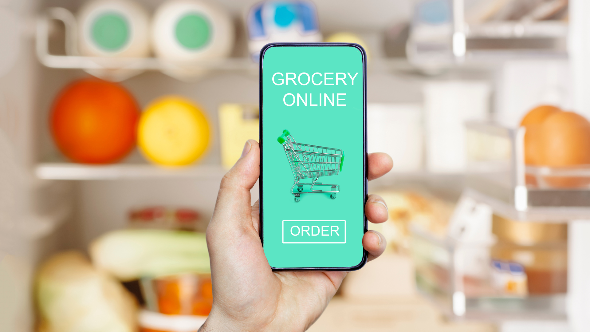 Hand holding a cellphone with the screen showing an online grocery store app with a shopping cart and an 'order' button.